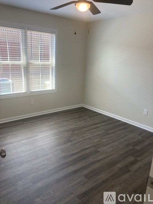 A room with a ceiling fan and a window with blinds.