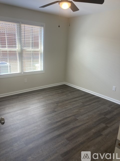 A room with a ceiling fan and a window with blinds.