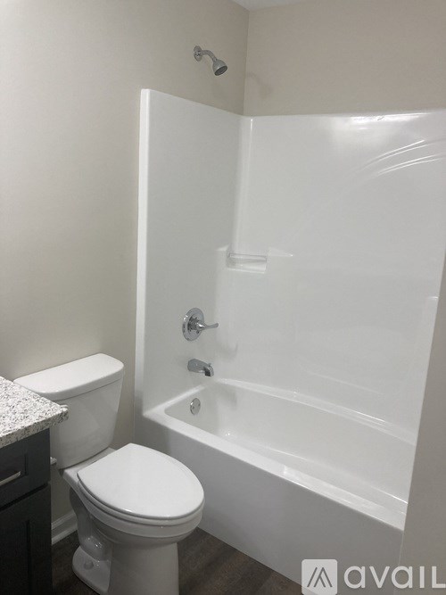 A white toilet sits next to a white bathtub in a bathroom.