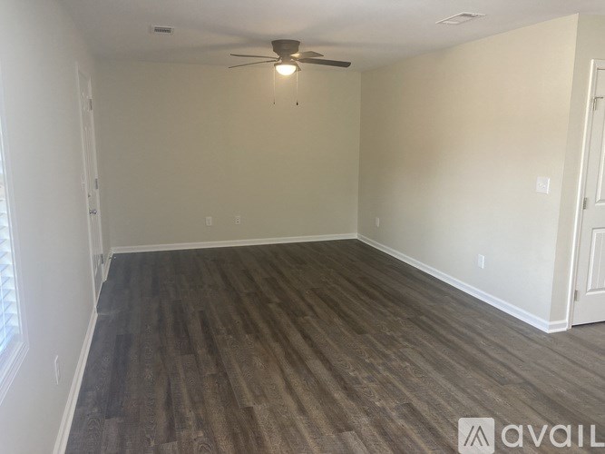 A room with a ceiling fan and wooden flooring.