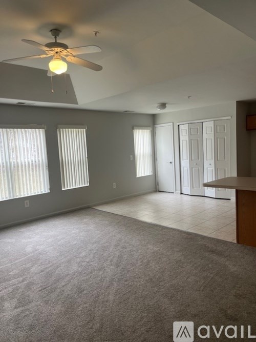 A room with a ceiling fan and carpeted floor.