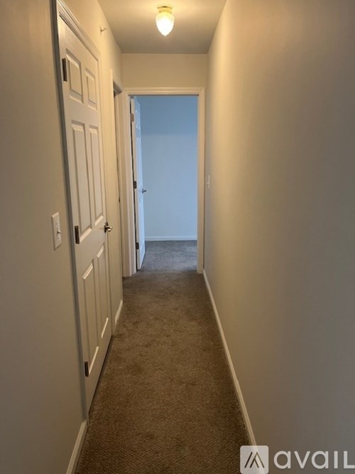 A hallway with a carpeted floor and white walls.