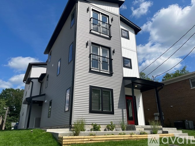 A grey house with a red door and a black awning.