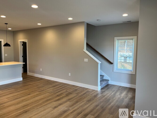A spacious room with wooden flooring and a staircase leading to another level.
