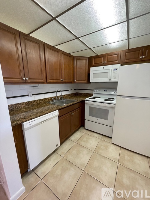 A kitchen with white appliances and brown cabinets.