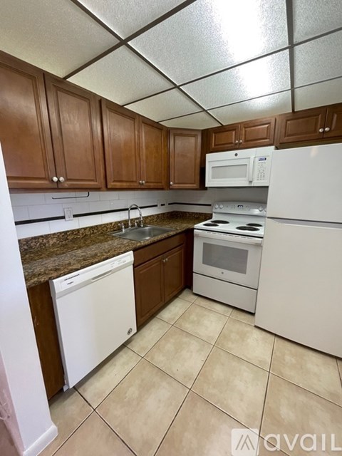 A kitchen with white appliances and brown cabinets.