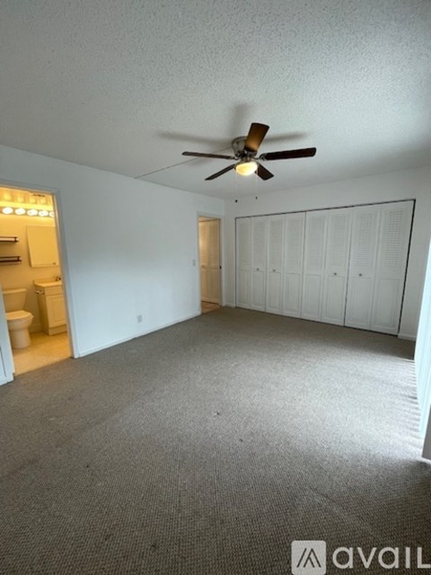 A room with a ceiling fan and a carpeted floor.