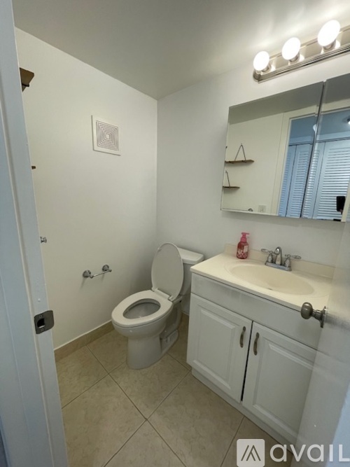 A bathroom with a toilet, sink, and mirror.