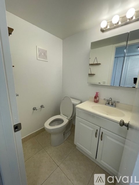 A bathroom with a toilet, sink, and mirror.