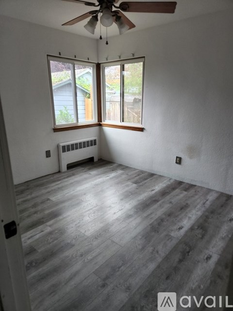 A room with a ceiling fan and a window overlooking a backyard.