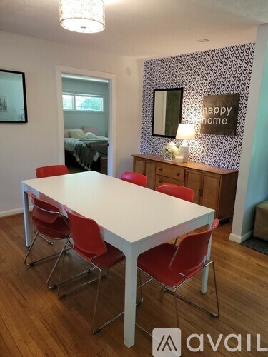 A white dining table with red chairs in a room.