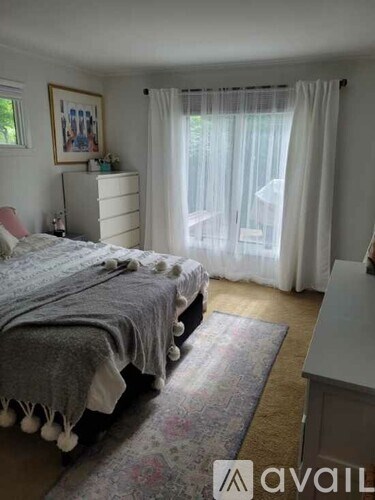 A bedroom with a bed, dresser, and window with curtains.