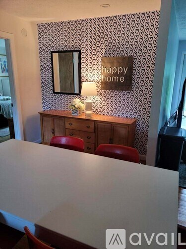A dining room with a white table and a wallpapered wall.