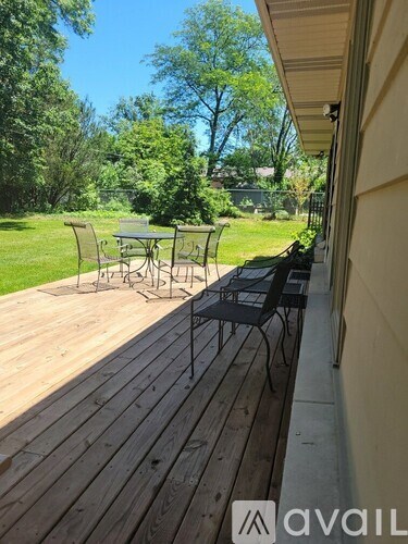A wooden deck with a table and chairs overlooks a green yard.