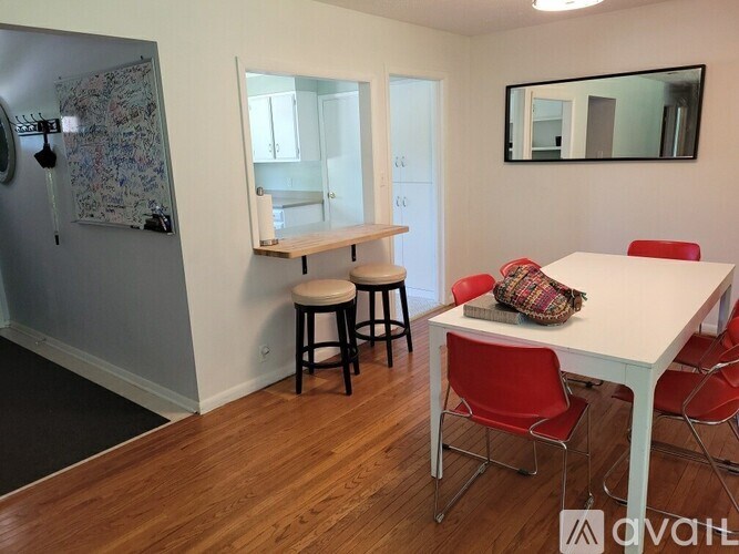A white dining table with red chairs in a room.
