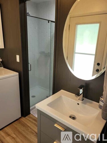 A bathroom with a round mirror, a sink, and a shower.
