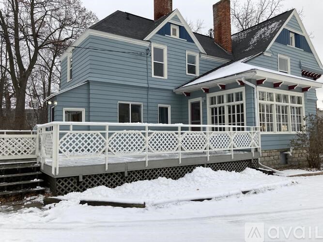 A blue house with a white porch and snow on the ground.