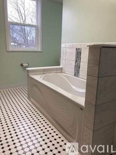 A white bathtub in a bathroom with a black and white floor.