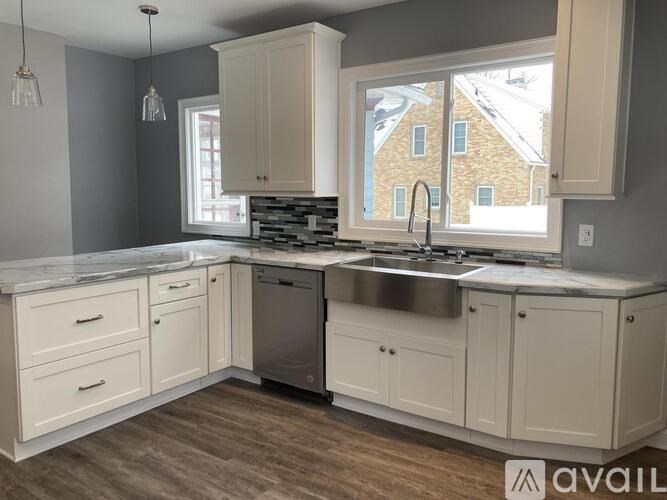 A kitchen with white cabinets and a marble countertop.