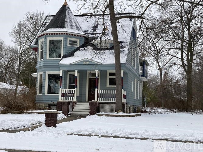 A blue house with a tower and a porch.