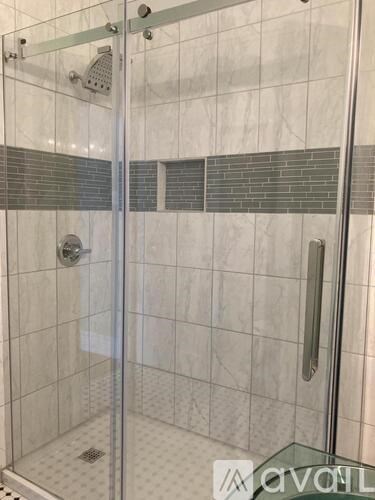 A glass shower door with a silver handle and a glass panel.