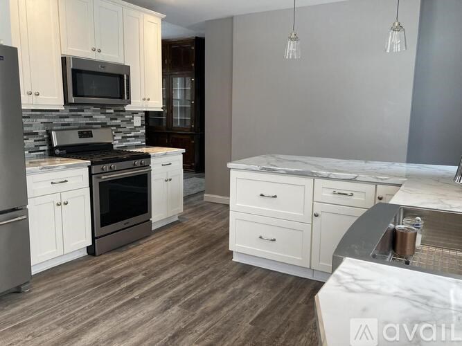 A kitchen with a stone backsplash and wooden floors.