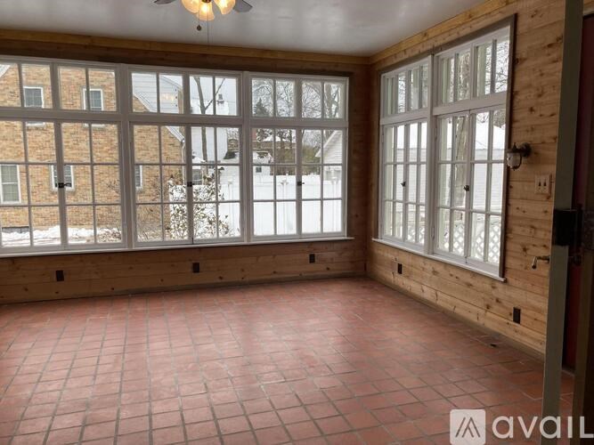 A room with wooden walls and a tiled floor with a view of a snowy landscape outside.
