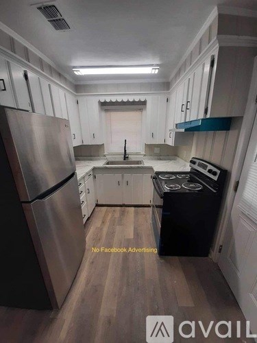 A kitchen with a stainless steel refrigerator and a black stove top oven.