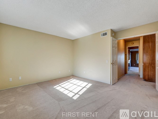 A spacious empty room with a carpeted floor and white walls.
