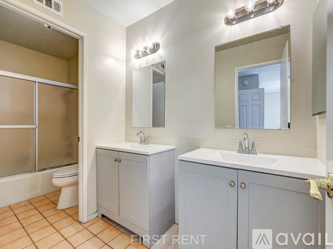 A balcony with a railing overlooks a field with trees and a blue sky above.