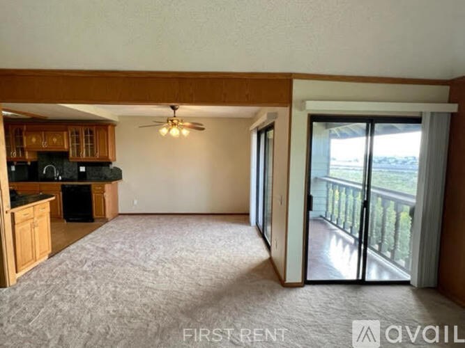 A living room with a ceiling fan and sliding glass doors leading to a balcony.