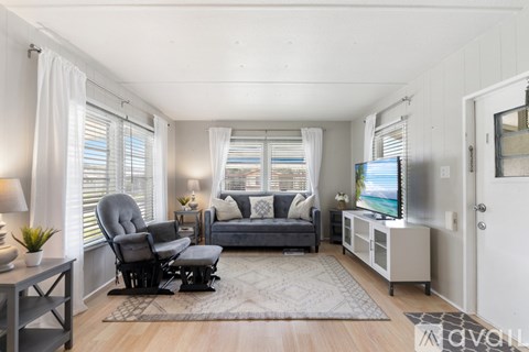 A living room with a grey couch, a chair, a table, and a television.
