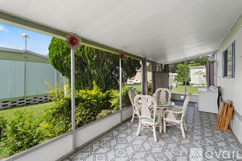 A patio with a table and chairs is covered by a white roof.