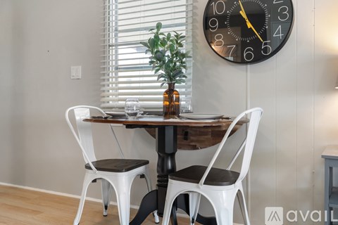 A table with two chairs and a clock on the wall.