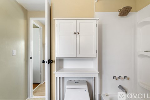 A white cabinet with a toilet underneath it in a bathroom.