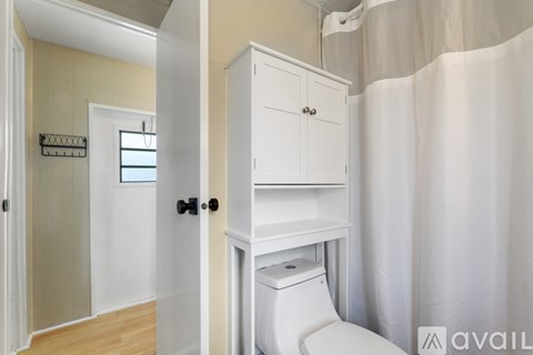 A white bathroom with a toilet and a cabinet.