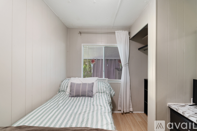 A bedroom with a bed and a window with curtains.