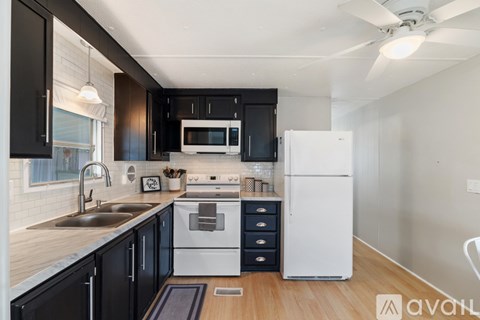 A modern kitchen with black cabinets and white appliances.