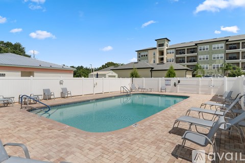 A pool surrounded by chairs and apartment buildings.