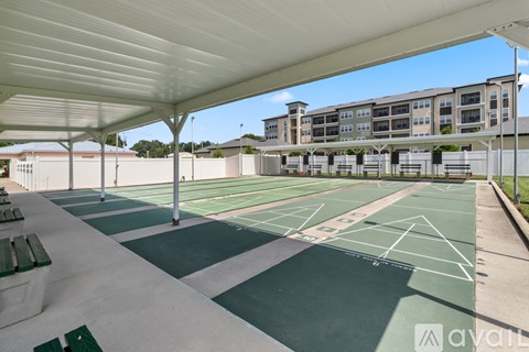 A tennis court is covered by a roof and has a green surface.