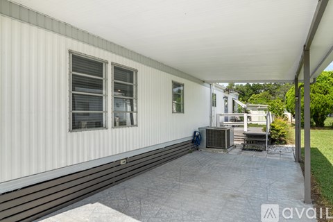 A white building with a covered patio and a grill.
