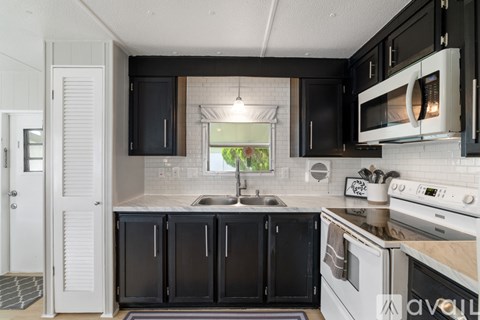 A kitchen with black cabinets and white appliances.