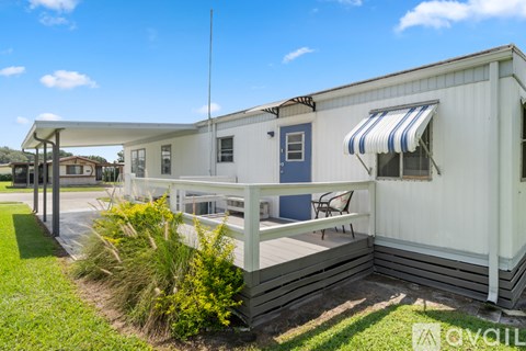 A white house with a striped awning and a blue door.