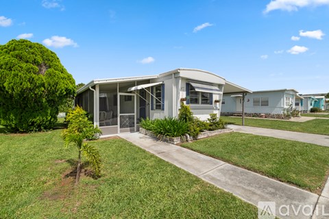 A house with a lawn and a tree in front of it.