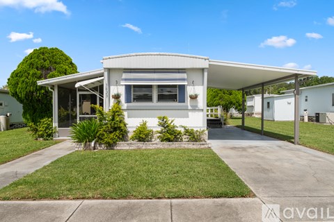 A white house with a covered patio and a green lawn.