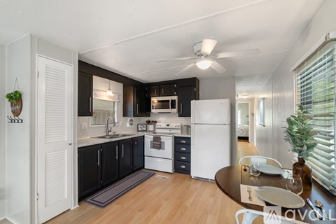 A modern kitchen with black cabinets and white appliances.