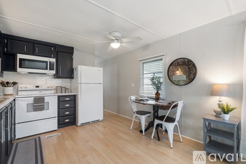 A kitchen with a white fridge and black cabinets.
