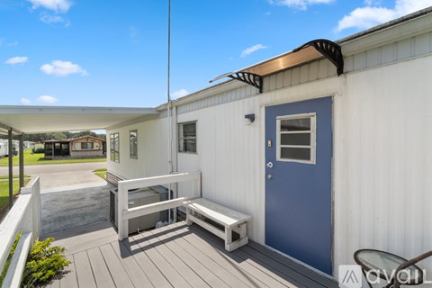 A white house with a blue door and a wooden deck.