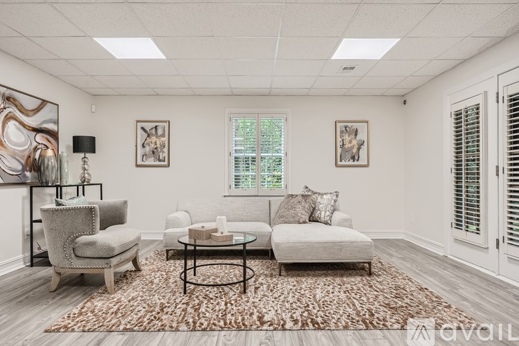 A living room with a grey sofa, a glass coffee table, and a rug.