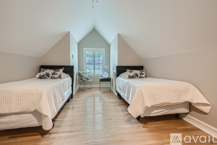 Two beds in a room with wooden floors and white walls.